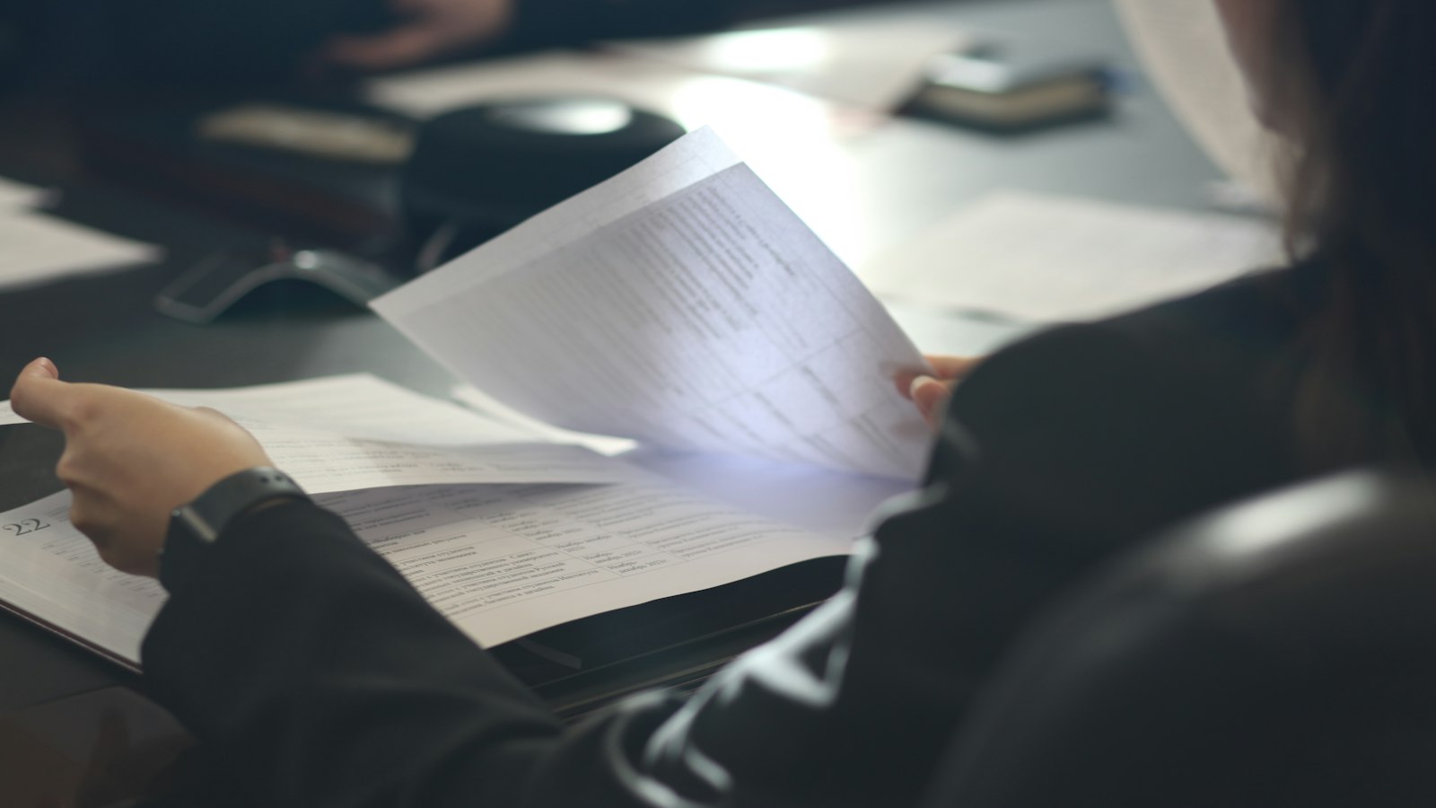 A woman at a table reading a printed document
