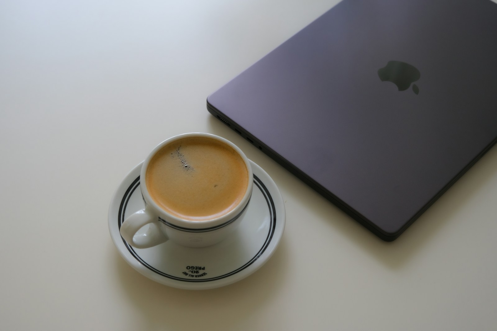 Coffee beside a closed laptop on a white table.
