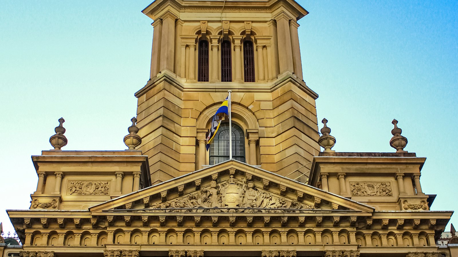 A historic sandstone civic building under a blue sky