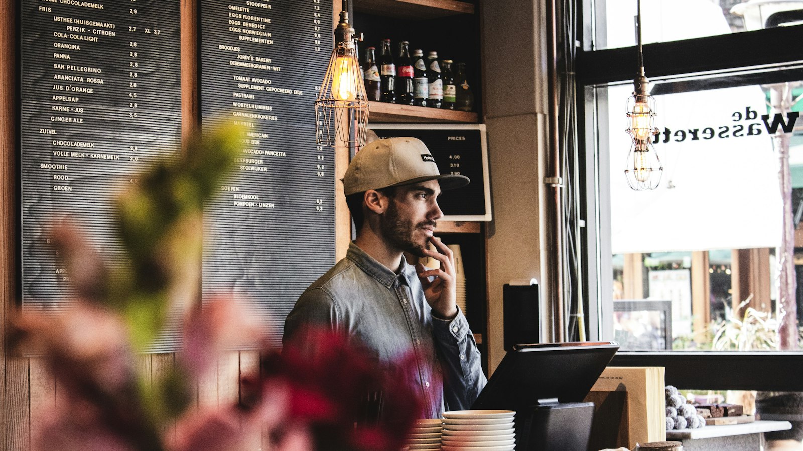 A cafe worker in front of a menu board