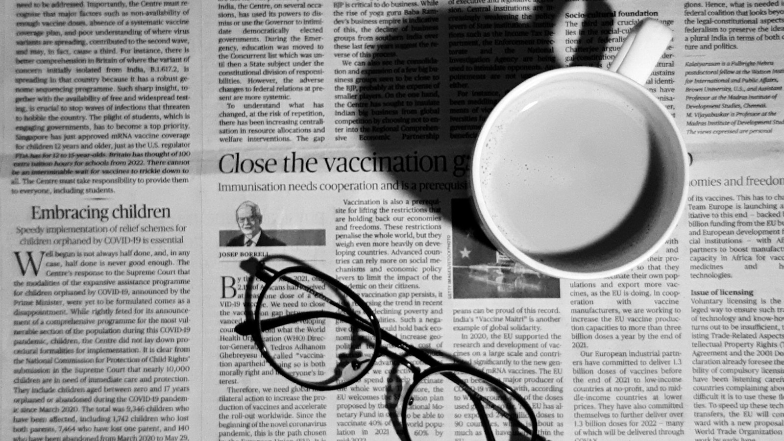 A cup of coffee and reading glasses on a newspaper
