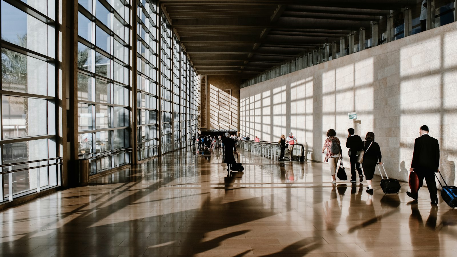 People walking through a sunlit airport terminal