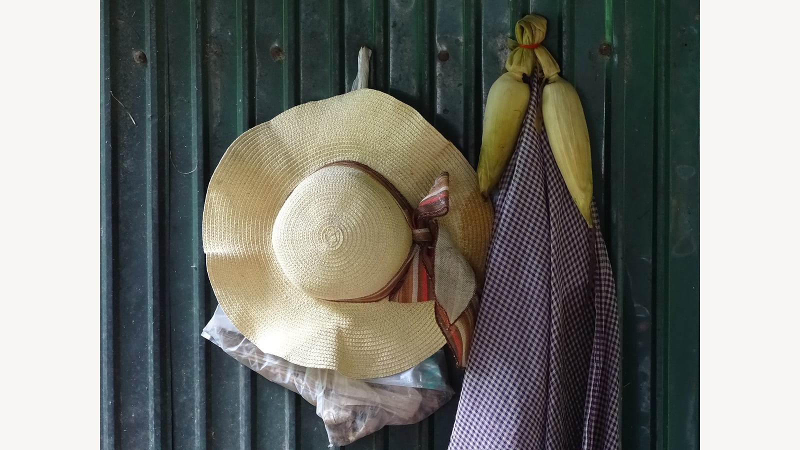 A broad-brimmed hat and cloths hanging on a wall in Cambodia. Illustrative sun-protection photograph.