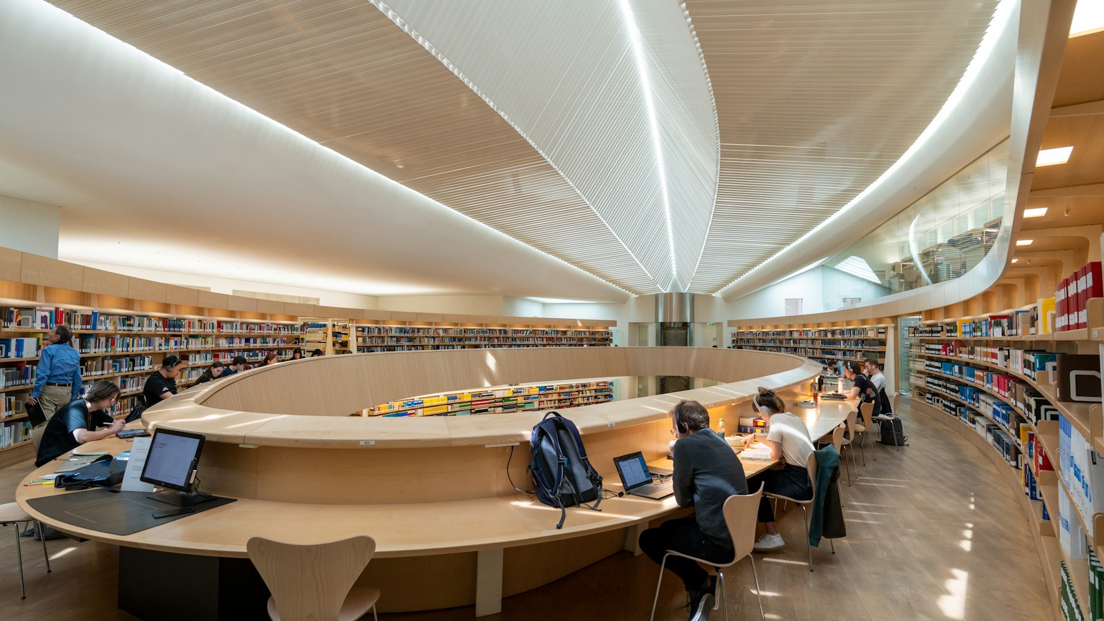 Students studying at tables in a large library
