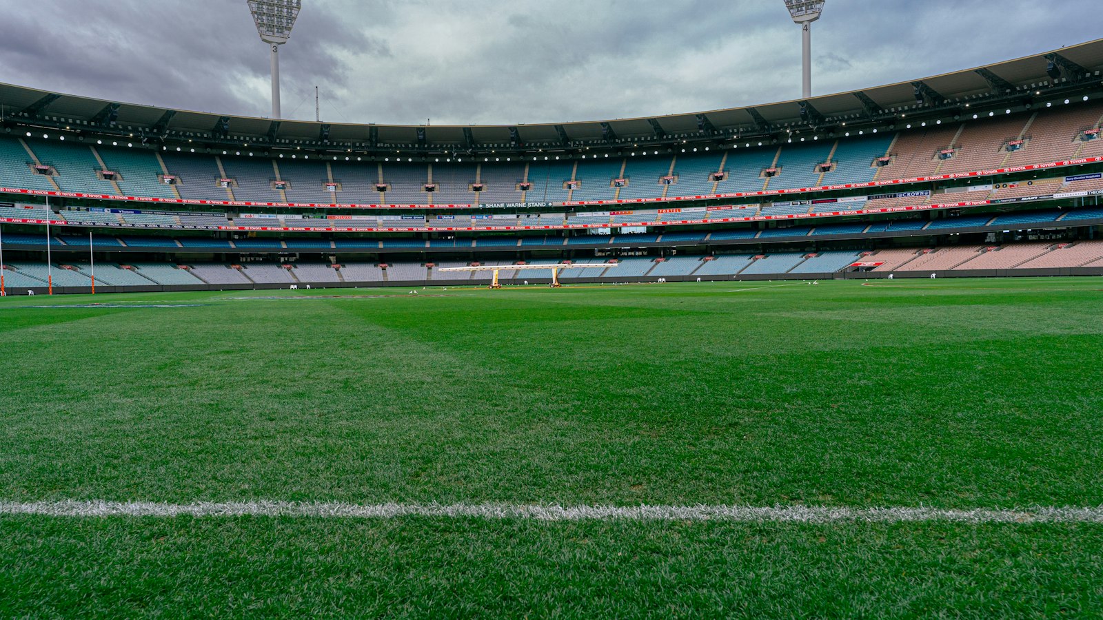 The Melbourne Cricket Ground with empty tiered seating under a cloudy sky