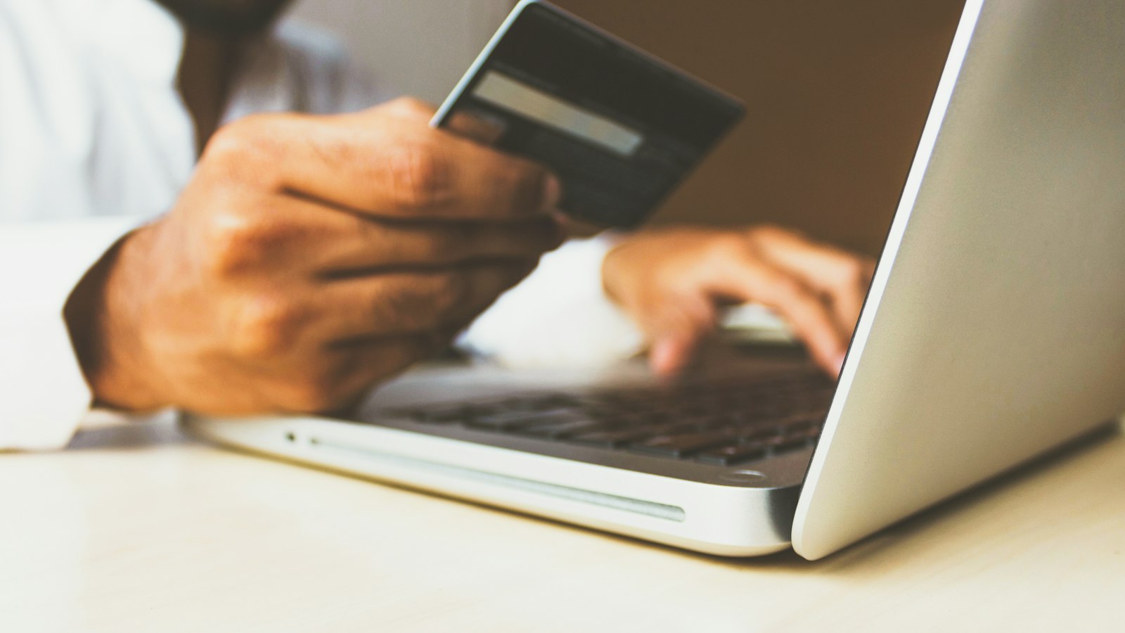 A person at a laptop holding a payment card
