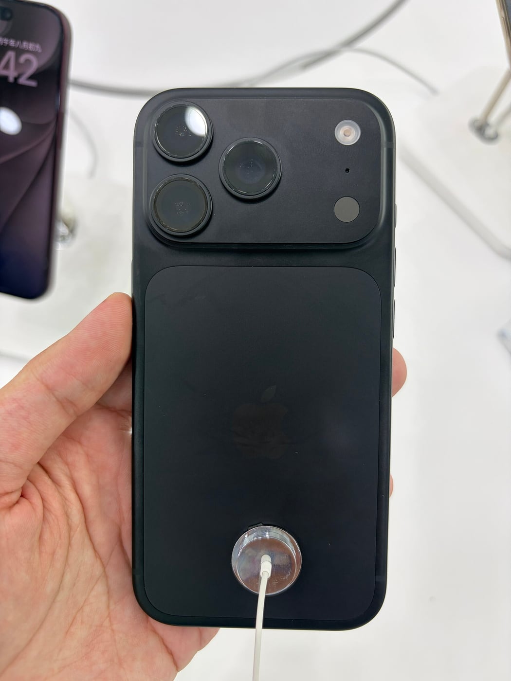 Rear of a black iPhone 18 Pro held in a hand.
