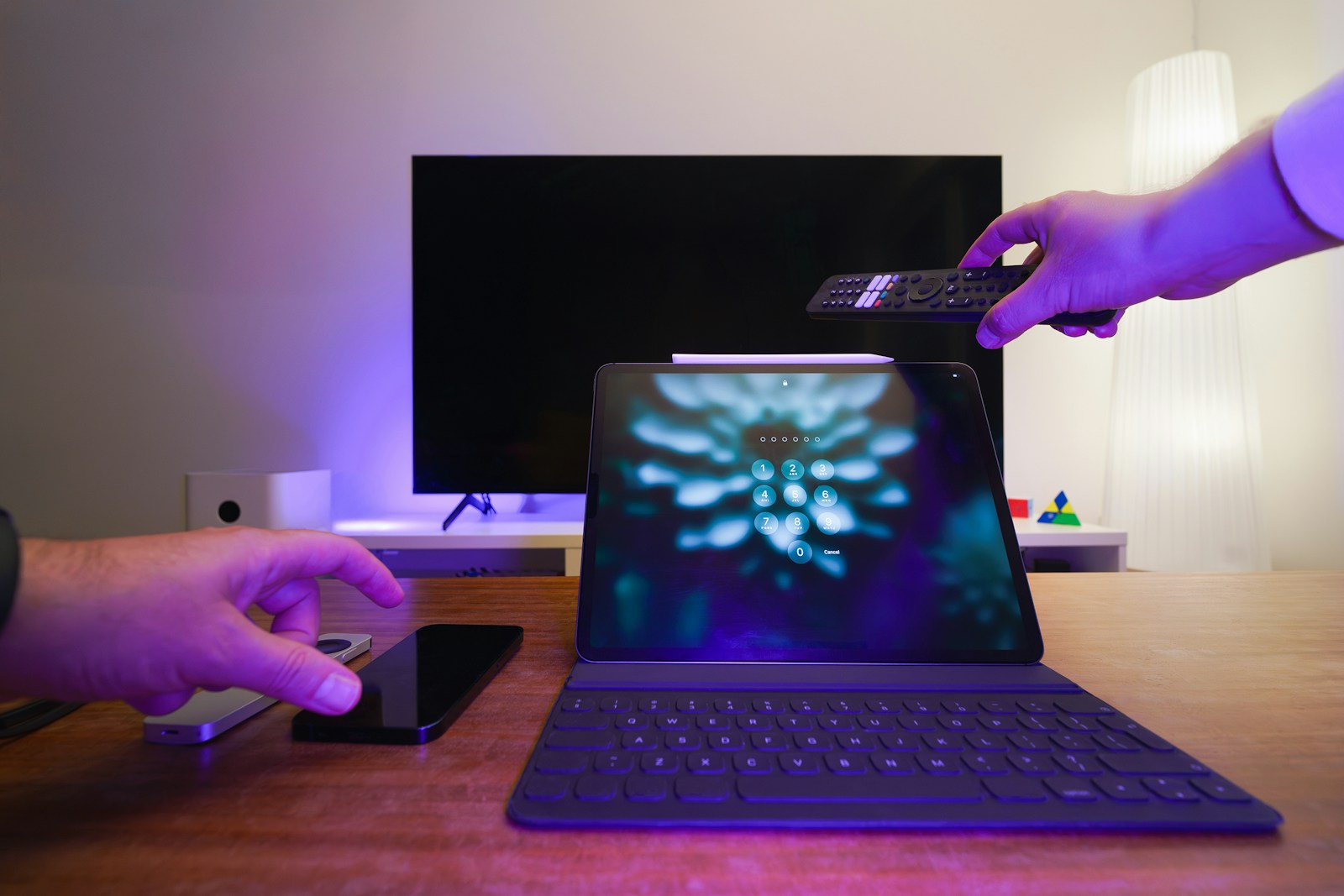 A person holding a remote control beside a laptop and television.