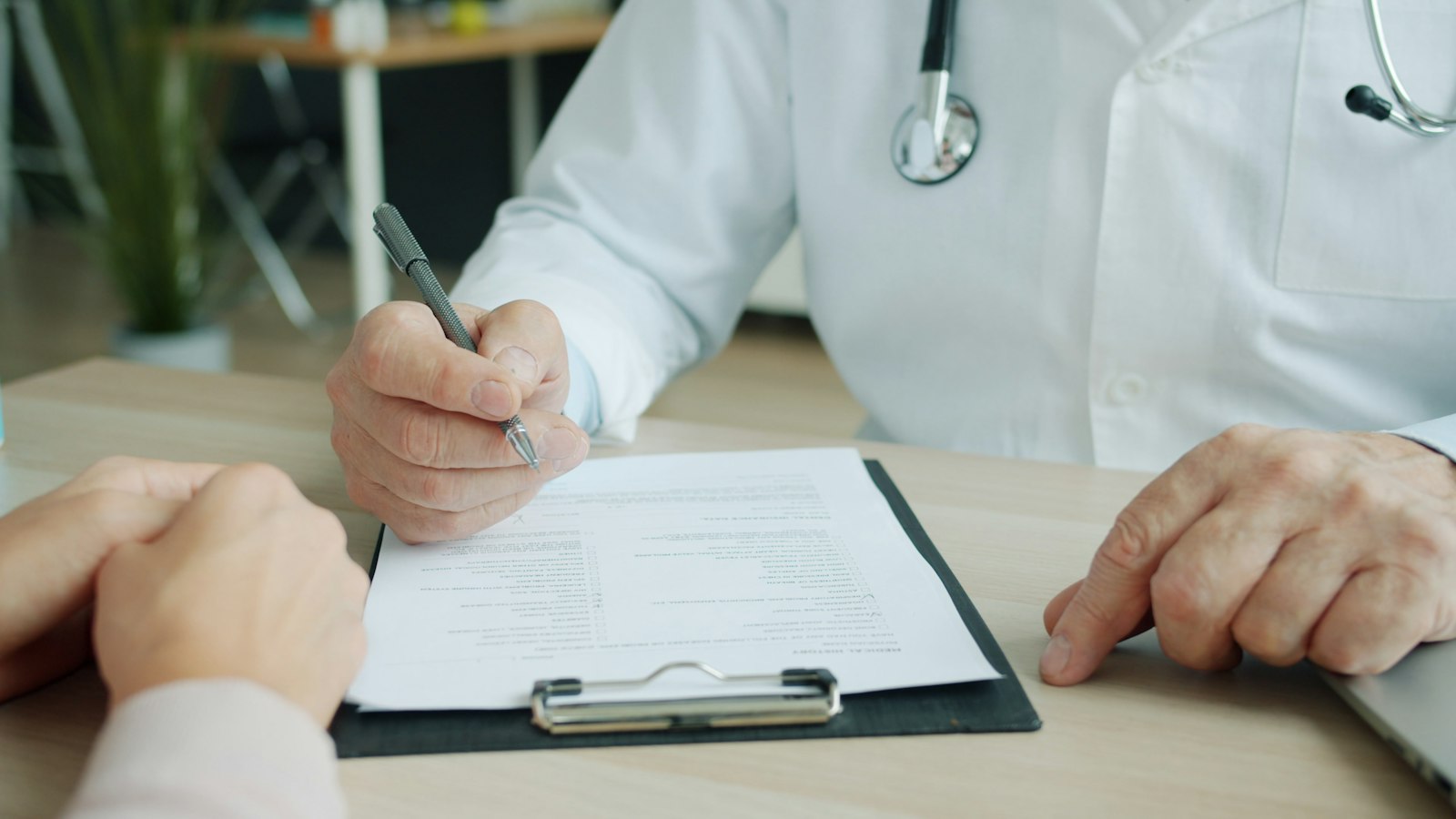 A doctor writing on a patient's chart