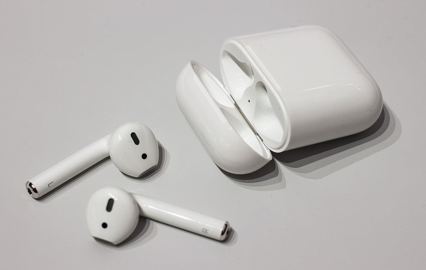 Earlier-generation Apple AirPods beside their charging case.