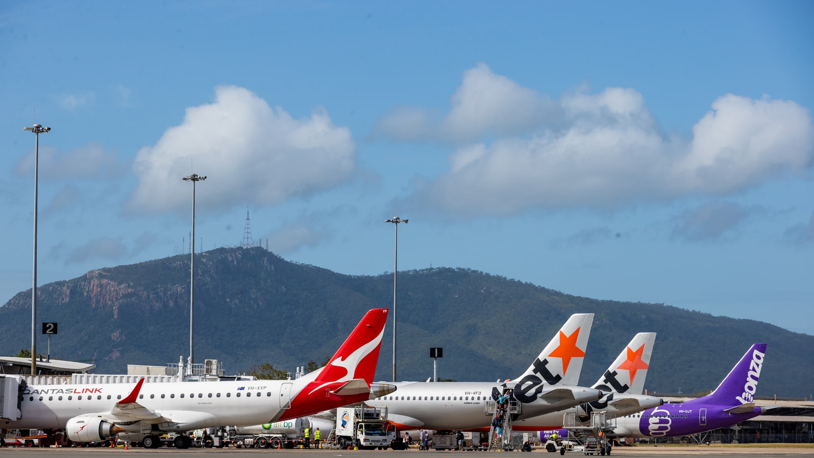Qantas, Jetstar and Bonza aircraft parked at Townsville Airport, with Mount Stuart behind (file photo)