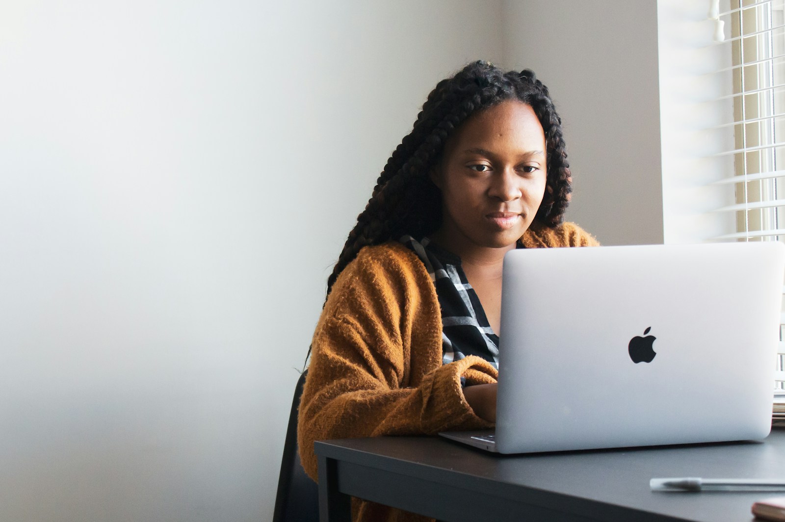 A woman with long braids using a laptop at a desk.
