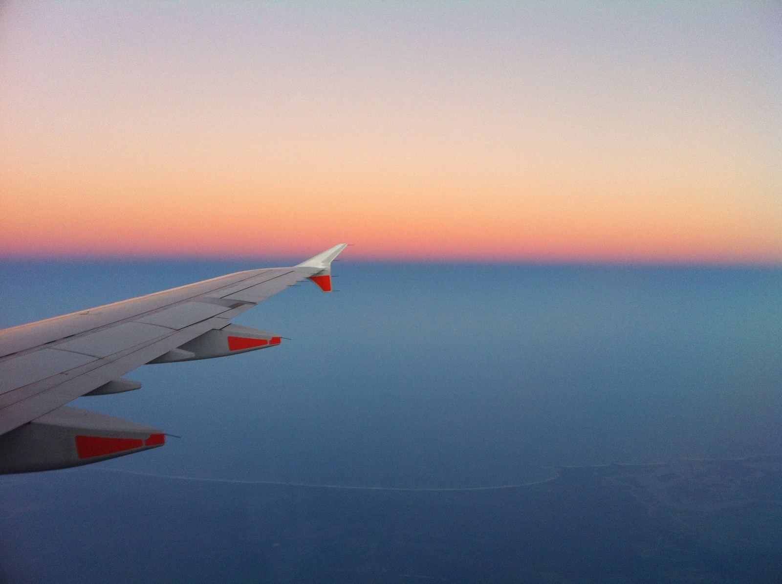 An aeroplane wing against a sunset sky.
